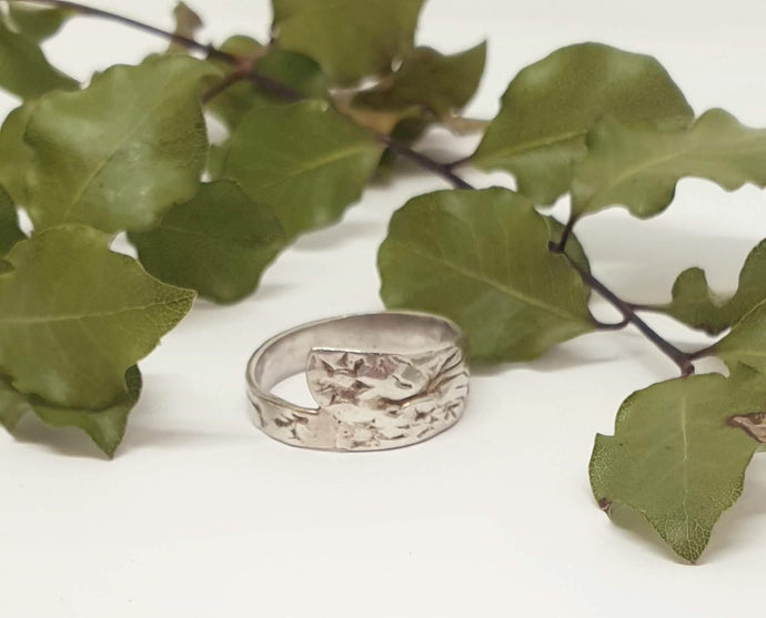 silver ring in front of leaves